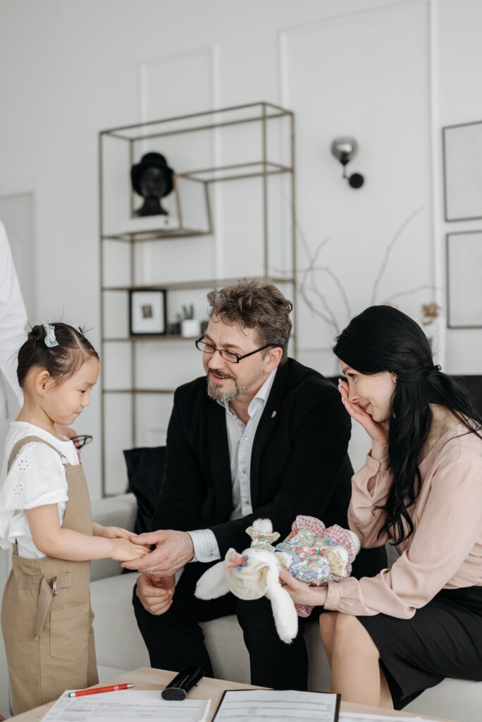 A joyful family scene featuring a couple with a young Asian child, depicting love and connection.