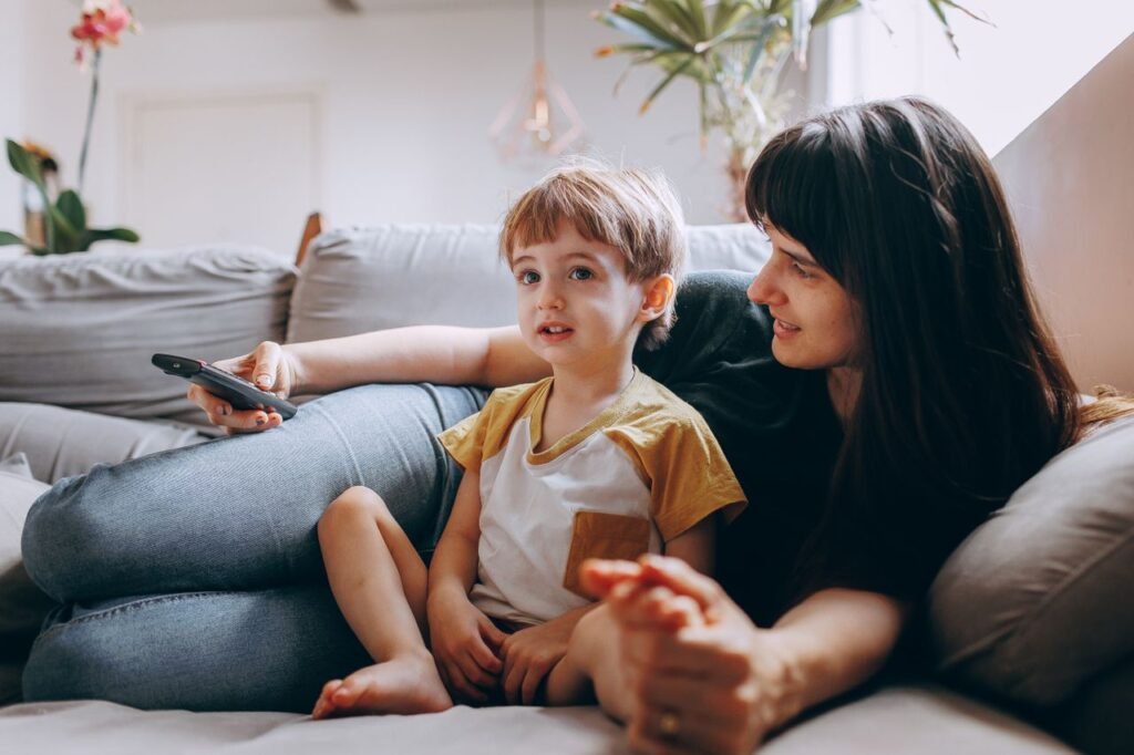 A mother and son spending quality time watching TV on a cozy couch at home.