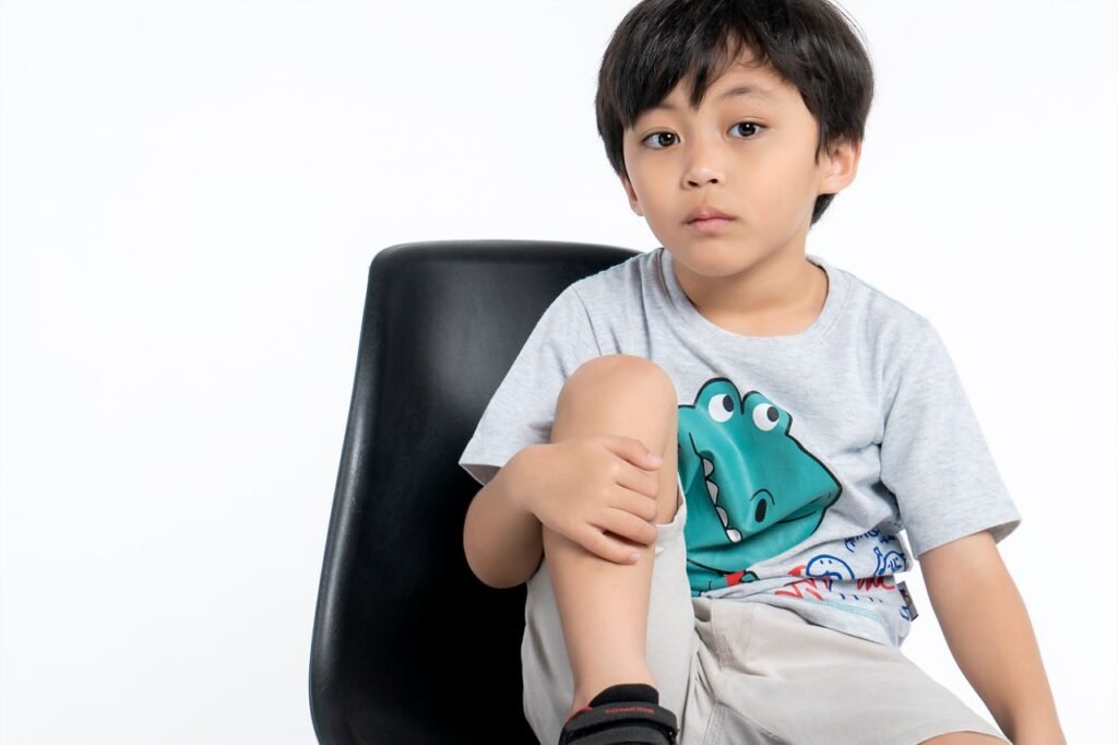 A young boy sits on a black chair in a studio setting, showcasing innocence and calmness.