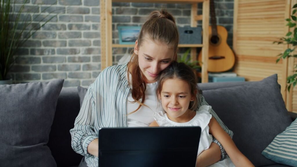 pexels-photo-36712816-36712816 Happy mother and daughter bonding while using a laptop in a cozy living room setting.