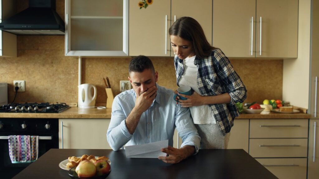 pexels-photo-36812196-36812196 Concerned couple reviewing financial document in modern kitchen setting.