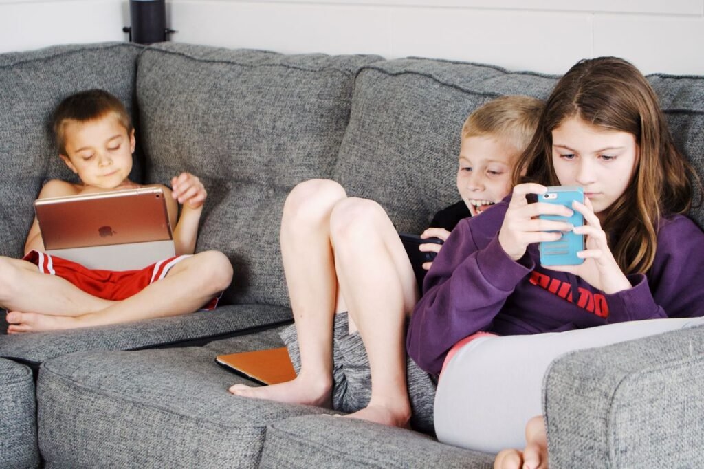 pexels-photo-4200824-4200824 Positive barefoot children in casual wear resting together on cozy couch and browsing tablets and smartphones