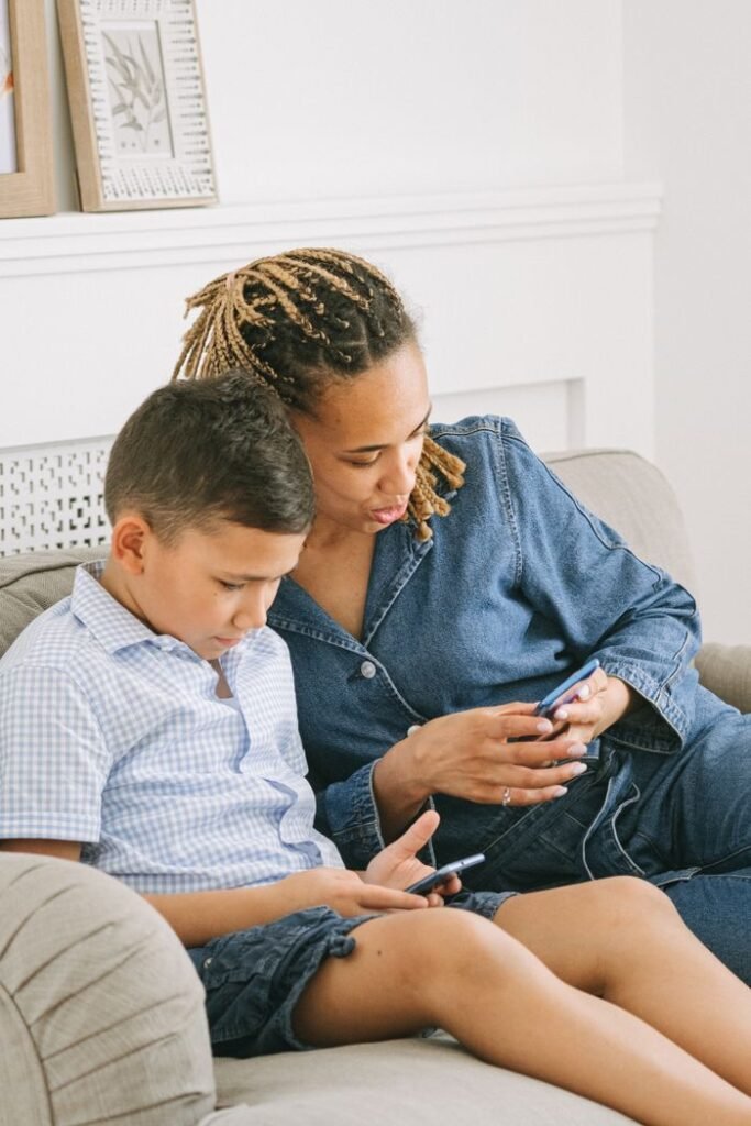pexels-photo-4624961-4624961 A mother and her son sit on a sofa, engaged with their smartphones indoors.