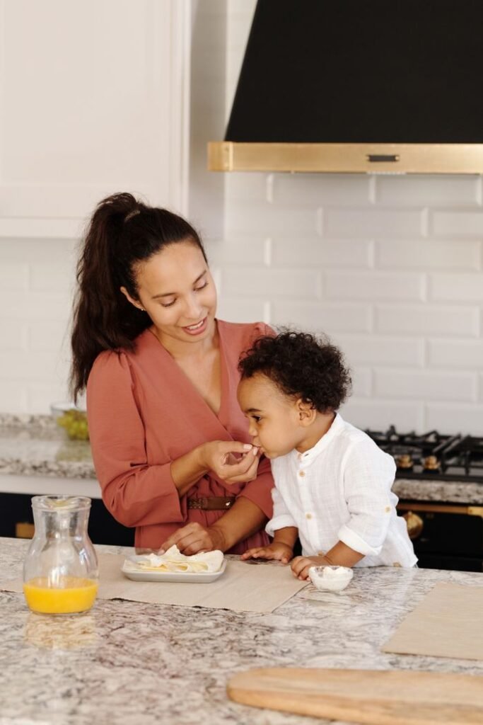 A loving mother feeds her son in a warm and welcoming kitchen environment.