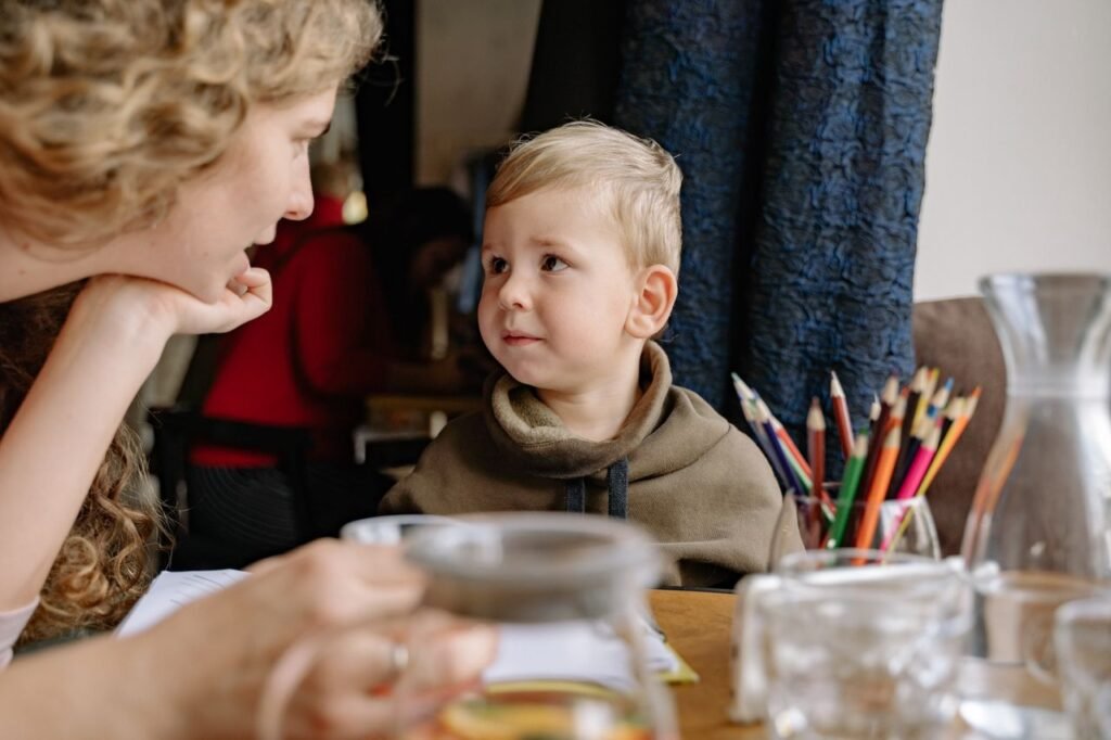 A mother and child engaging in creative drawing time with colored pencils at a cozy indoor setting.