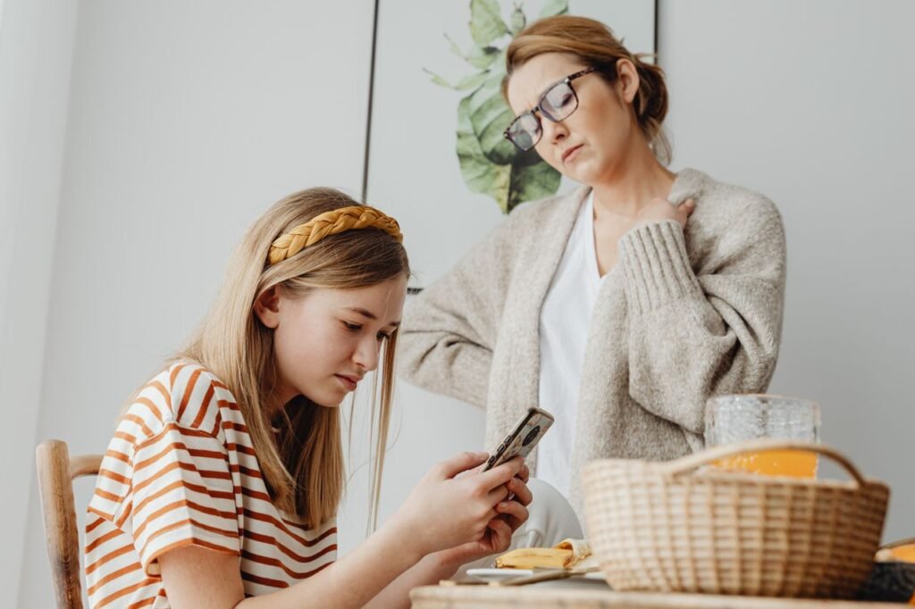 pexels-photo-6957245-6957245 A mother discusses with her daughter engrossed in her phone during breakfast indoors.