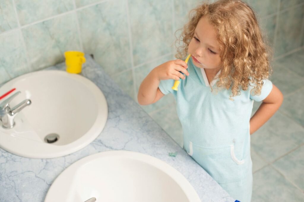 pexels-photo-12645015-12645015 Child brushing teeth by sink, highlighting personal hygiene habits.
