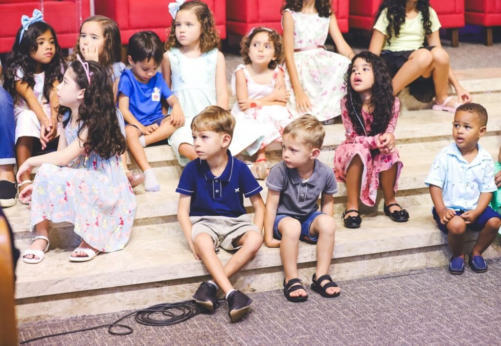 pexels-photo-30472679-30472679 Children attentively sit on marble steps indoors, dressed in colorful summer clothing.