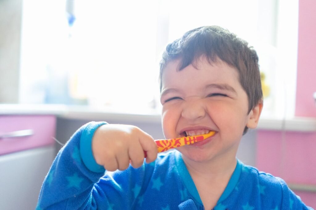 pexels-photo-4185330-4185330 A cheerful young boy in pajamas brushing his teeth in a brightly lit bathroom.
