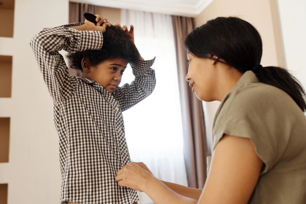 pexels-photo-4260751-4260751 A caring mother helps her son brush his hair and button his shirt indoors.