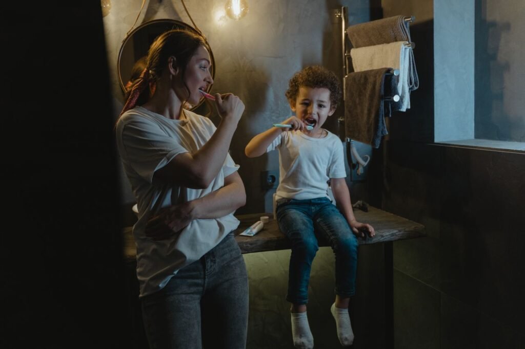 pexels-photo-6336778-6336778 A mother and son brush their teeth together in a warmly lit bathroom, promoting good hygiene habits.