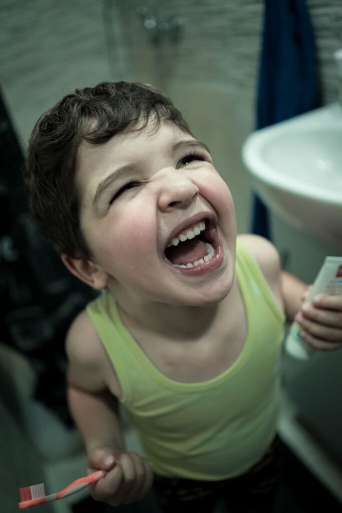 pexels-photo-6543057-6543057 From above of little delighted boy with toothpaste and toothbrush learning cleaning teeth in bathroom
