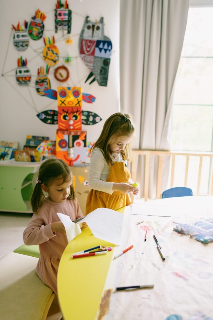 pexels-photo-8535626-8535626 Two young girls crafting in a colorful preschool classroom, surrounded by art supplies and handmade decorations.
