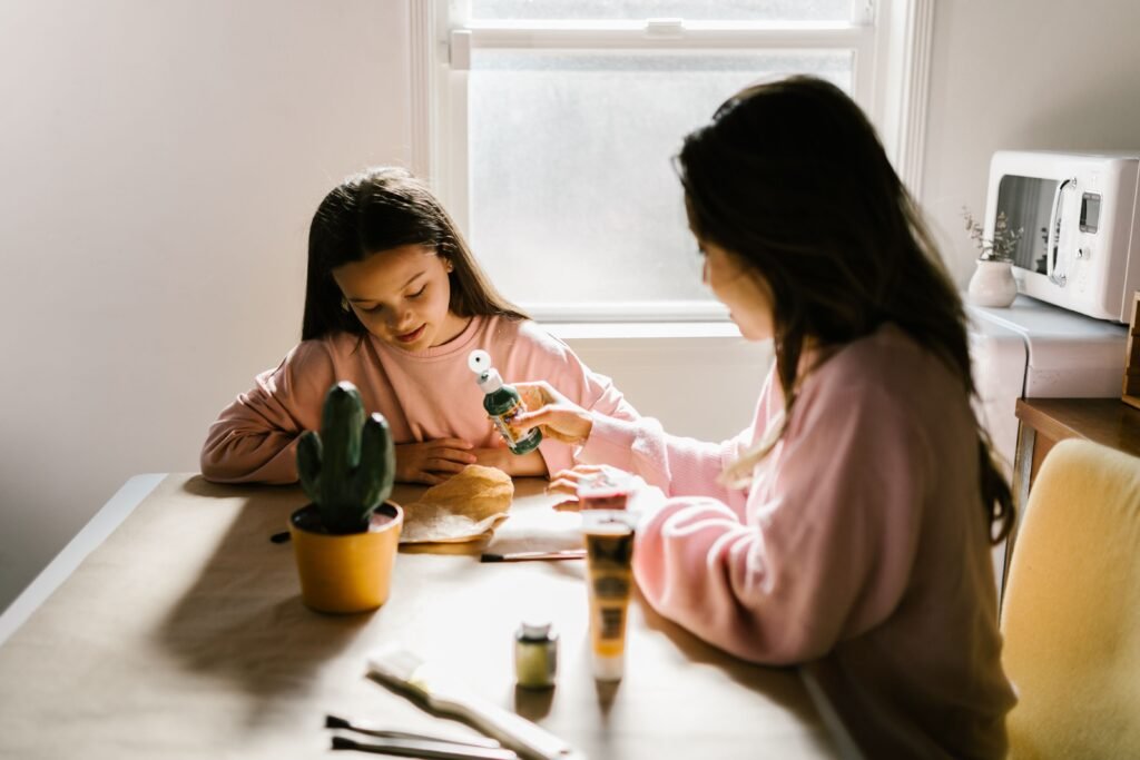A mother and daughter enjoying a craft project together by the window.